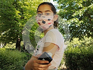 Diabetes and Corona virus. Girl with the mask on face reads glucose level in blood with CGM device