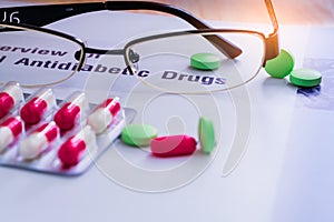 Diabetes drugs and glasses placed on textbook. Diabetes mellitus type 2 concept.