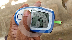 Diabetes machine in hand prick finger to make punctures to obtain small blood specimens for blood glucose, using glucose meter