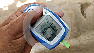 Diabetes machine in hand prick finger to make punctures to obtain small blood specimens for blood glucose, using glucose meter