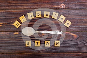 Diabetes STOP block wooden letters and sugar pile on a spoon. Concept Diabetes Prevention