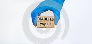 Diabetes type 2 medical concept. Hand in blue glove holds wooden blocks with the inscription `diabetes type 2`. Beautiful white