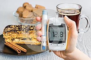 Diabetes and unhealthy eating concept. Hand holds glucometer and sweets.