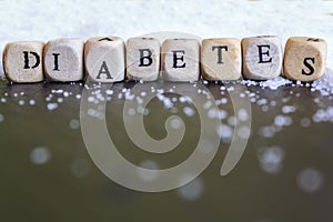Diabetes word written on wooden cubes with pile of sugar on the background