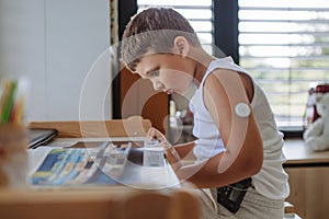 The diabetic boy doing homework, while wearing a continuous glucose monitoring sensor on his arm.