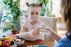 Diabetic girl drinking water to better manage her diabetes. Continuous glucose monitor sensor on girl& x27;s arm.