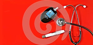 Diabetic measurement set next to stethoscope on red background.