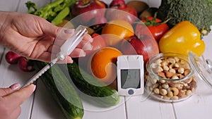 Diabetic woman dialling insulin into a syringe on the background of fresh fruits