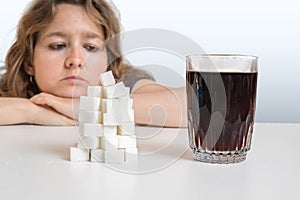 Diabetic woman is looking on glass with cola drink and heap of sugar. Unhealthy eating concept