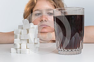 Diabetic woman is looking on glass with cola drink and heap of sugar. Unhealthy eating concept