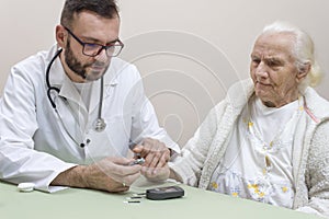 Diabetologist punctures the finger of a woman suffering from diabetes.