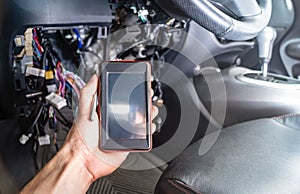 Diagnosis of car faults: a portable auto scanner with OBD2 interface in the electrician`s hand. On the background of the