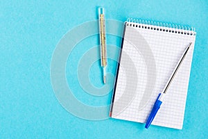 Diagnosis of the disease. Notebook with pen and pills on a blue background