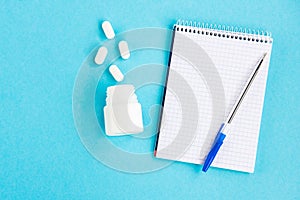 Diagnosis of the disease. Notebook with pen and pills on a blue background