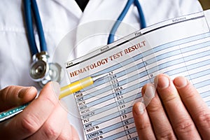Diagnosis in hematology and hematological blood tests concept photo. Doctor holds in his hand result of blood test and indicates w photo