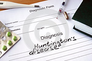 Diagnosis Huntingtons disease and tablets on a wooden table.