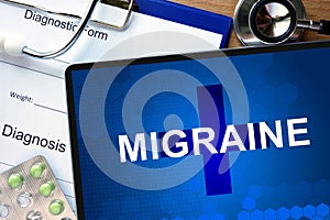 Diagnosis Migraine and tablets on a wooden table.