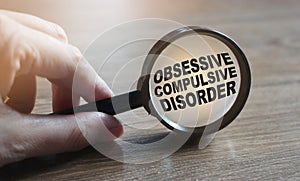 Diagnosis of Obsessive Compulsive Disorder under magnifying glass in hand. Causes, symptoms, diagnosis and treatment of this photo