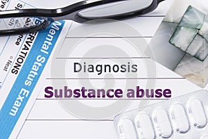 Diagnosis Substance Abuse. Medical notebook labeled Diagnosis Substance Abuse, psychiatric mental questionnaire and pills are on t