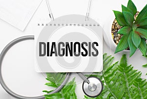 Diagnosis word on notebook,stethoscope and green plant