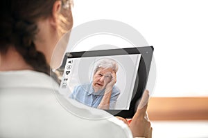 Diagnostic and consultation with the telemedicine, doctor holding a tablet, elderly woman with headache