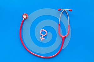 Diagnostic and cure of gynaecological disease with stethoscope and female symbol on blue background top view