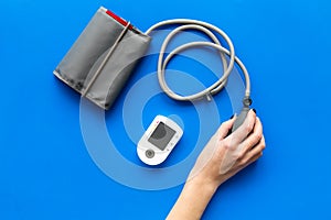 Diagnostics of cardiac disease with pulsimeter on blue background top view