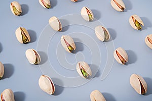 Diagonal arranged rows of fresh pistachio nuts with hard shadows, pattern background