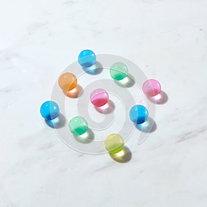 Diagonal pattern from hydrogel color balls on a grey marble table.