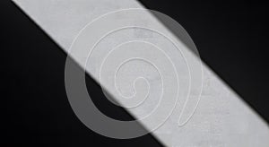 Dramatic diagonal shadow striking textured concrete surface, modern abstract light and dark contrast