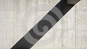Diagonal shadow creating geometric pattern on a weathered concrete wall surface