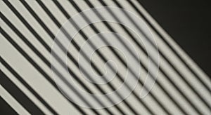 Diagonal shadows of parallel lines cast on a surface, creating a pattern of alternating light and