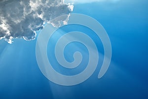 Diagonal sunbeam on a blue sky under a cloud