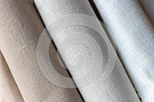 Diagonal textural background of three types of natural linen fabric, rolled up