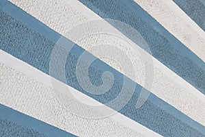 Diagonal view of blue and white parget striped wall background. Sharp surface.