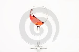 Diagonal wave of rose wine, alcohol is in glass on white isolated.