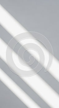 Diagonal white light beams on a gray surface create a minimalist, abstract pattern. The