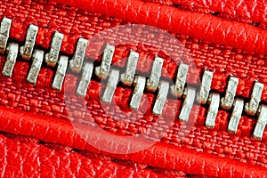 Diagonal zipper tightly closed binding together two layers of red fabric textile and red leather under high magnification detail
