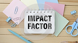 diagram on white big notepad, green book and paper sheet with text IMPACT FACTOR. Business concept