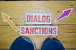 Dialog or Sanctions opposite direction signs with sneakers on wooden