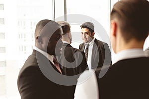 Dialogue of two men with with smartphones young businessmen in suits working and communicating together in an office