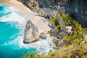 Diamond beach with ocean, coconut palms and rock in Nusa Penida