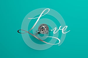 A diamond engagement ring as the letter `O` in the handwritten word LOVE on tiffany blue background