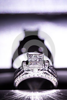 A diamond engagement ring. in a box with glint/reflection. Shimmering princess-cut diamonds.