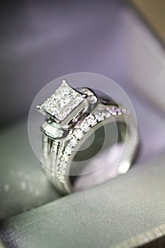 A diamond engagement ring. in a box with glint/reflection. Shimmering princess-cut diamonds.