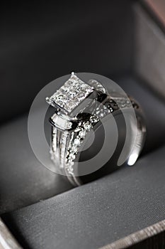 A diamond engagement ring. in a box with glint/reflection. Shimmering princess-cut diamonds.