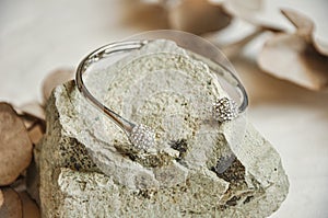 Diamond gold bracelet on stone with eucalyptus leaves, white background