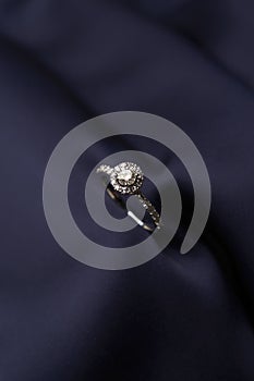 Diamond ring with carat gemstone on a blue silk background