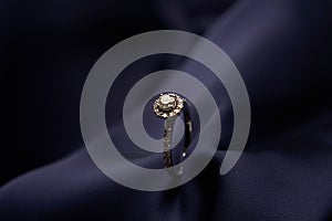 Diamond ring with carat gemstone on a blue silk background