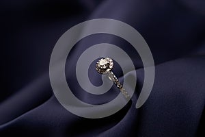 Diamond ring with carat gemstone on a blue silk background